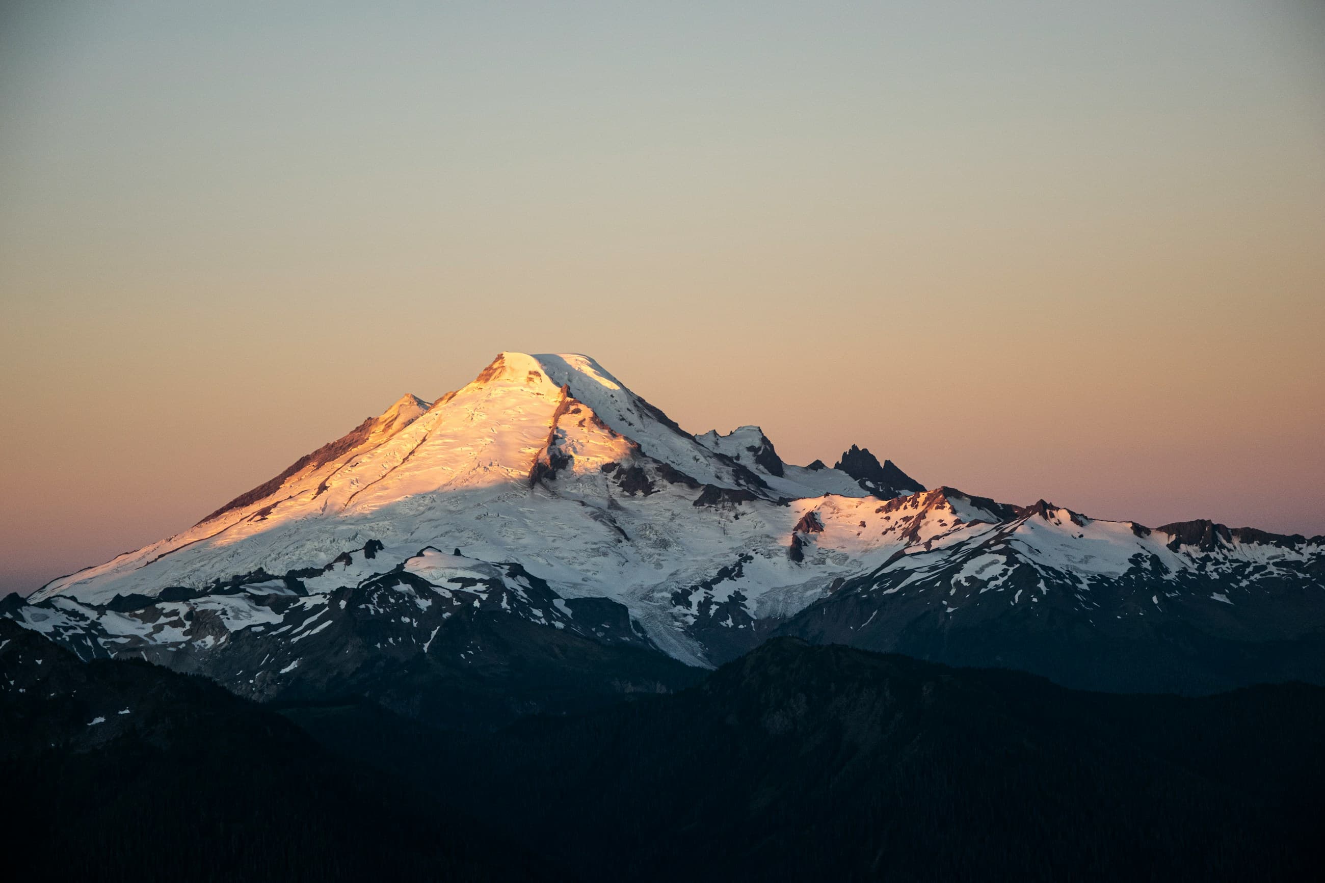 Snow-covered peak glowing with alpenglow at dusk
